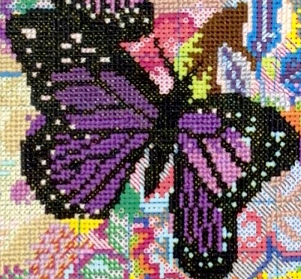 a picture of a purple butterfly made via cross stitch